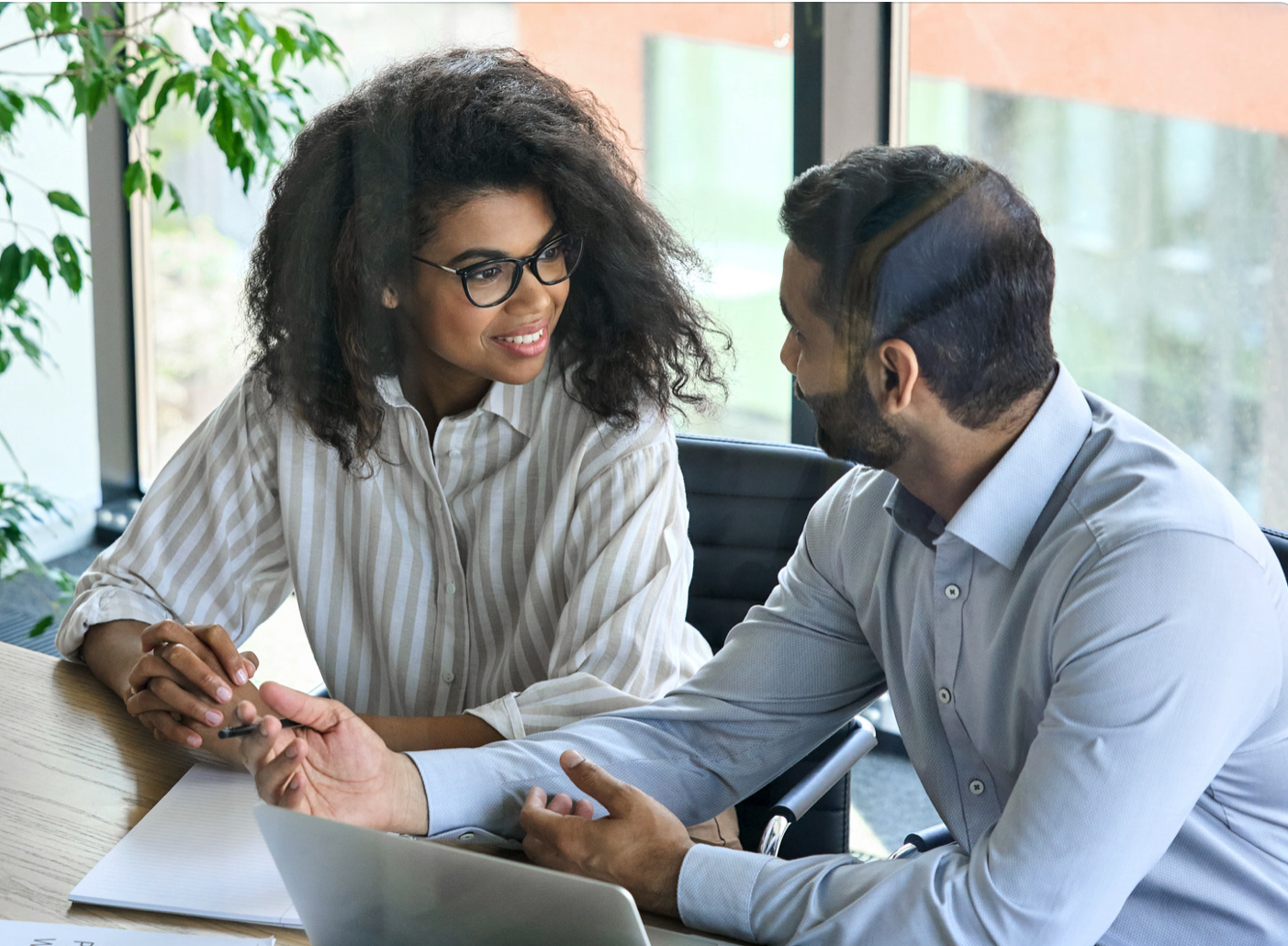 people of color talking to each other with computer and notepad