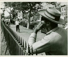 historic image of man leaning on fence wearing hat