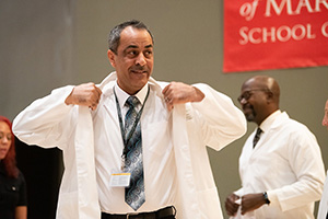 A student puts on a white coat during the White Coat Ceremony.