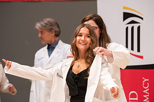 A student receives a white coat from a faculty member.