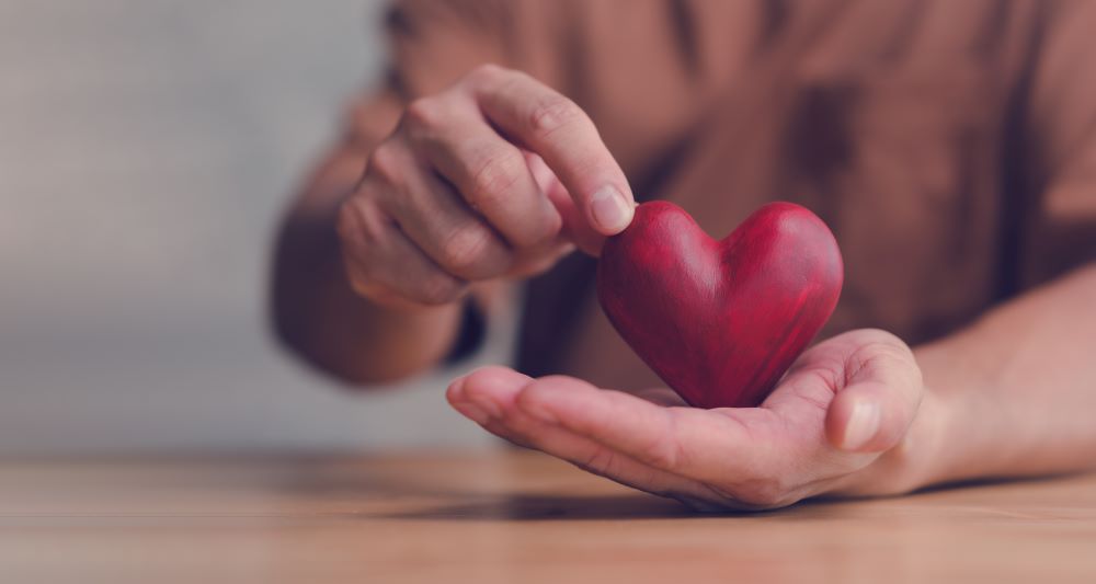 holding a wooden heart in hands