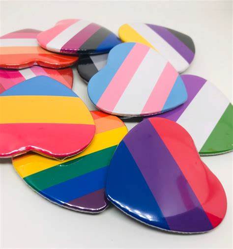 A collection of heart-shaped buttons depicting a variety of LGBTQIA flags. 