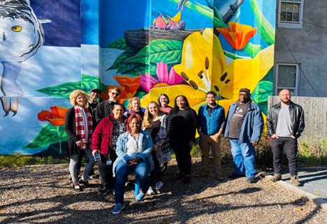 group of people standing in front of mural