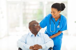 Nurse smiling at older adult patient in a wheelchair
