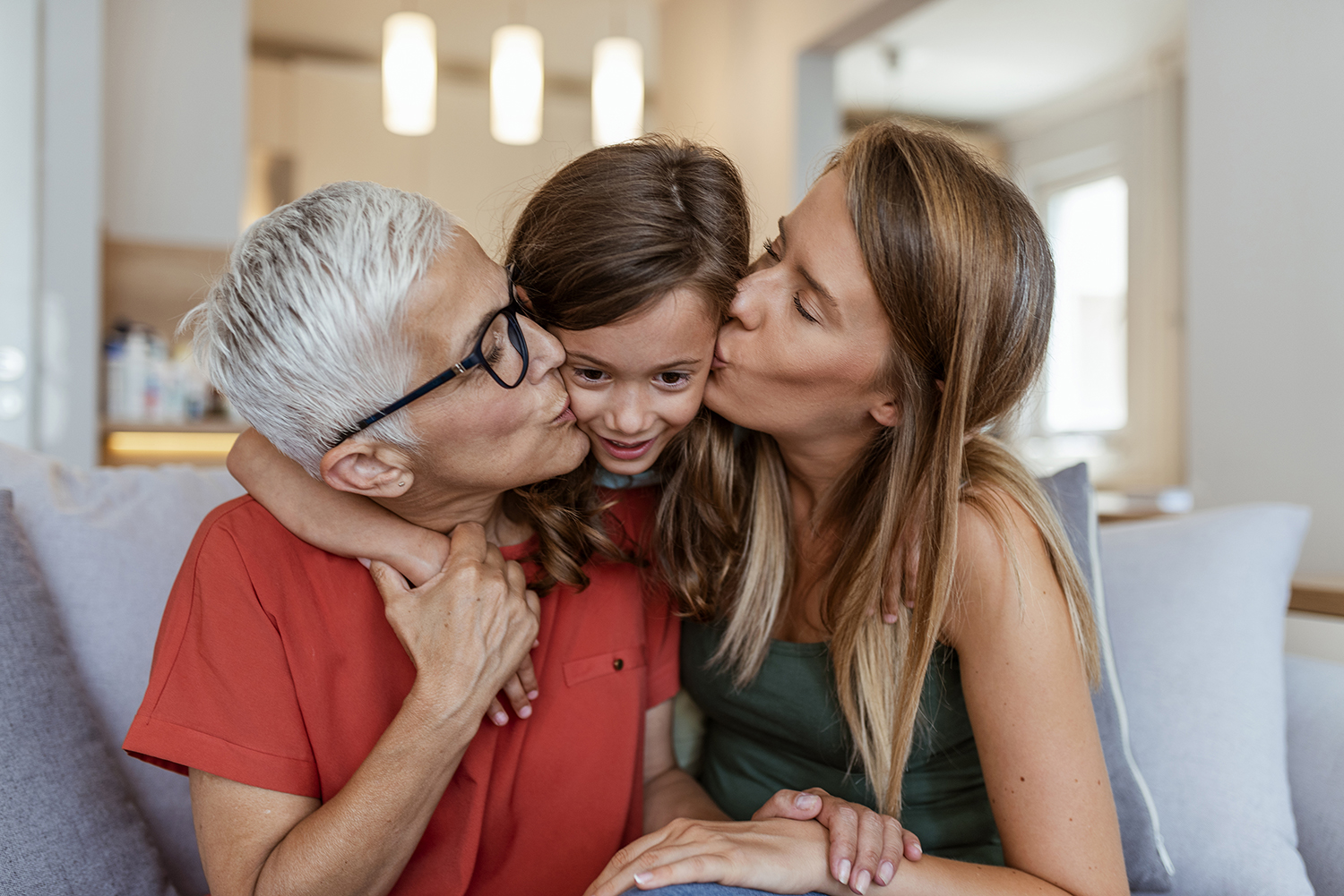 Older woman and younger woman kissing small child's cheeks