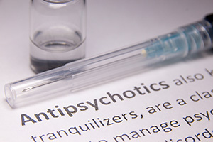 An image of a vial, needle, and the word antipsychotics