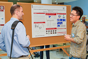 Two people discuss research during the poster session at the CADD symposium.