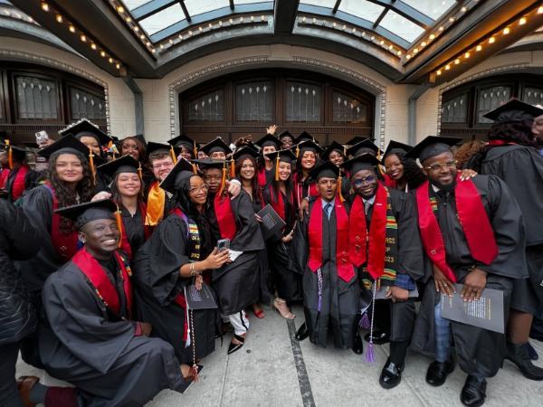 photo of group of graduating students in regalia in front of the Hippodrome Theatre