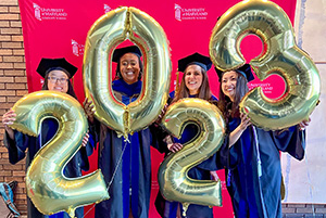 PhD graduates holding balloons that say 2023.