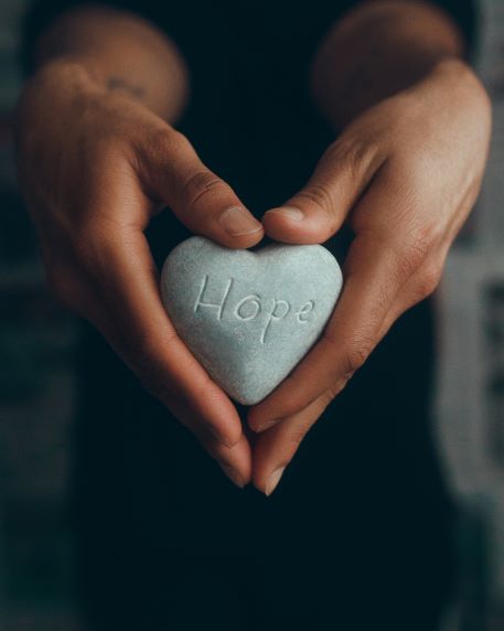 Image alt text: Hand holding heart-shaped rock with ‘hope’ Photo by Ronak Valobobhai on Unsplash
