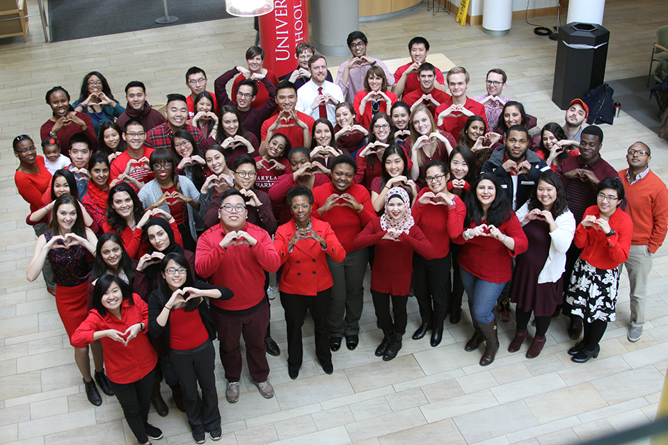 Group at UMB wearing red and making a sign with their hands of a heart