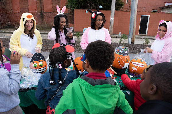 Three students from UMSOD Dental Hygiene hand out candy to youth attending the 2022 Trick or Treat with UMB.