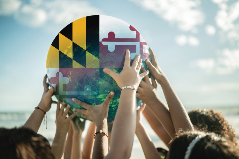 image of diverse hands holding up a globe that's replaced with the Maryland flag motif