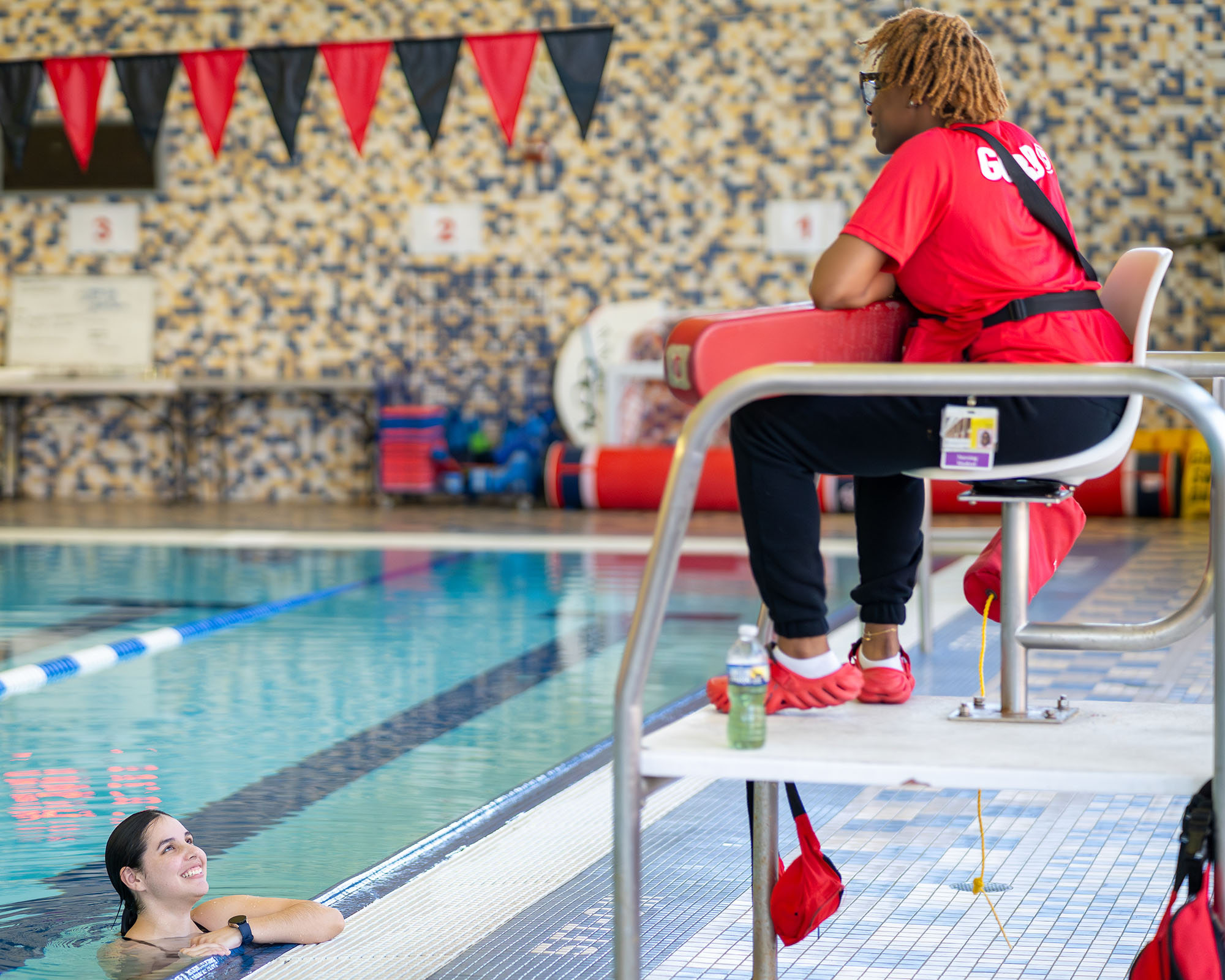 a student in the indoor swimming pool smiling at lifeguard