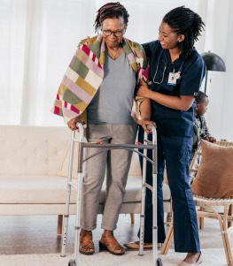 woman in health care uniform helps older woman with walker