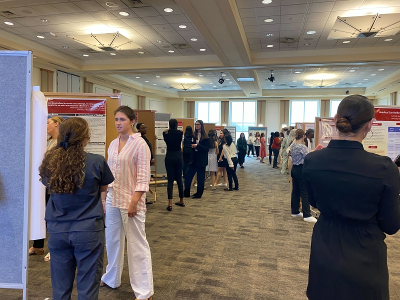 poster day with students standing around posters talking to others