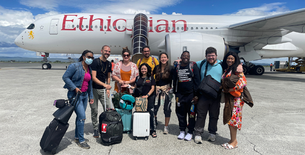 Students pose for a photo in front of an airplane in Tanzania