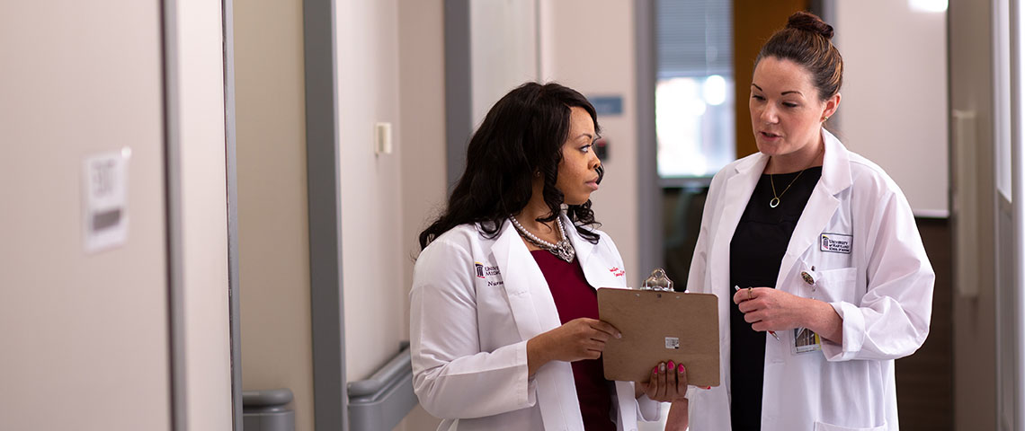 image of two nurses in white coats talking in a hallway