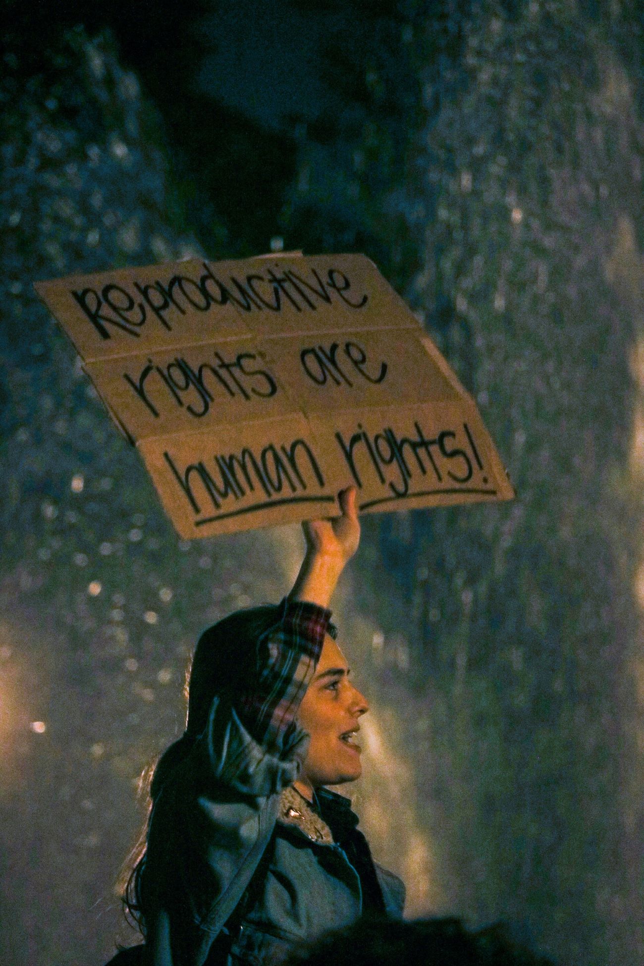 Individual holding a cardboard sign with the words 