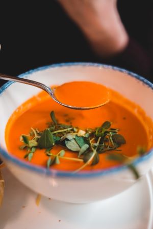 spoonful of soup above a bowl of tomato soup. Photo by Erik Mclean on Unsplash