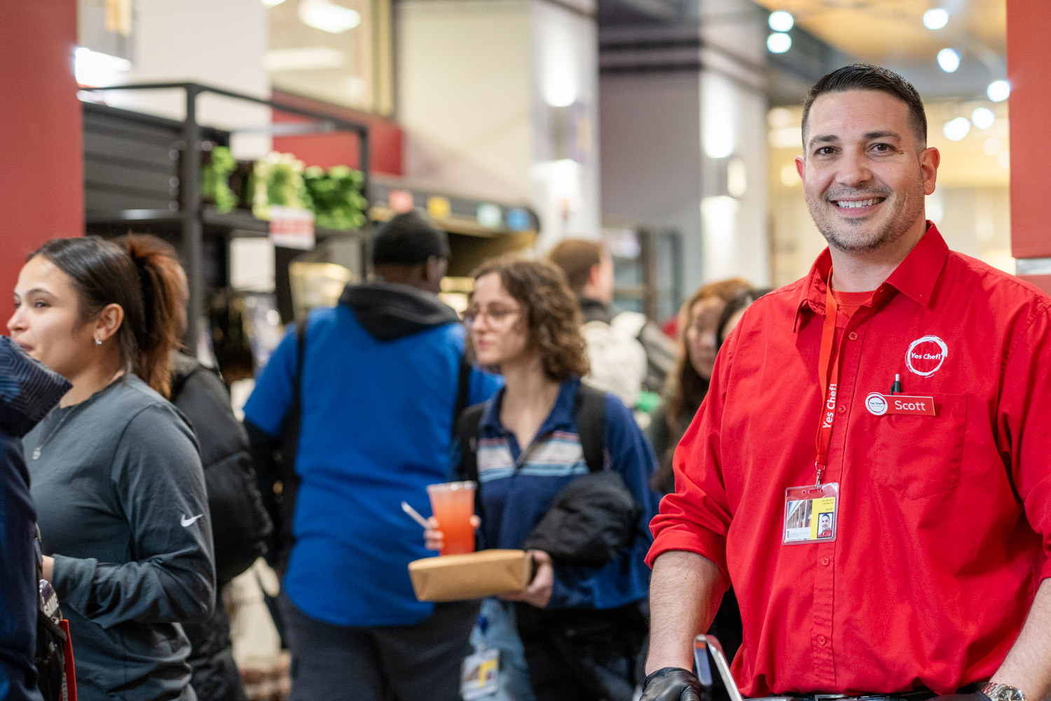 Man in red shirt standing in campus center