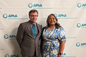 Jim Polli and Cherokee Layson-Wolf pose in front of an APhA backdrop at the annual meeting.