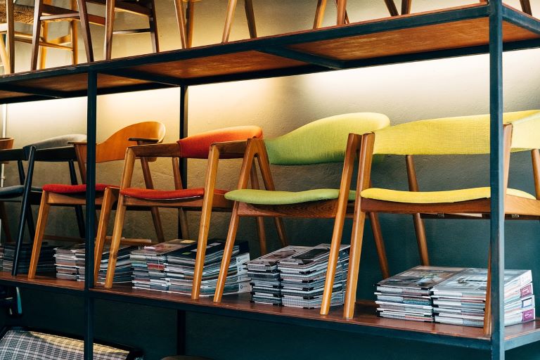 green, yellow and orange chairs lined up with stacks of papers underneath