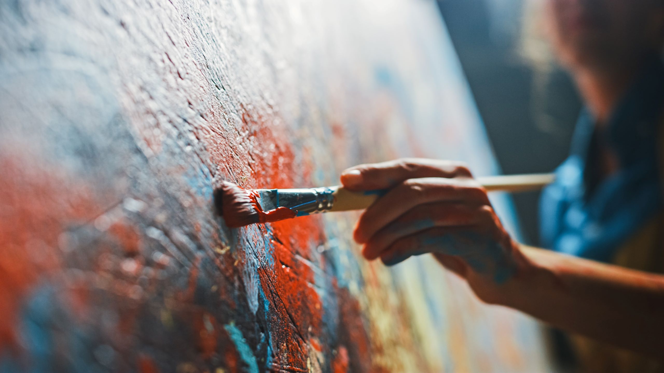 Close up of a painter holding a brush and painting on a canvas