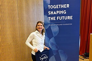 Nicole Brandt in front of a sign that says Together Shaping the Future.