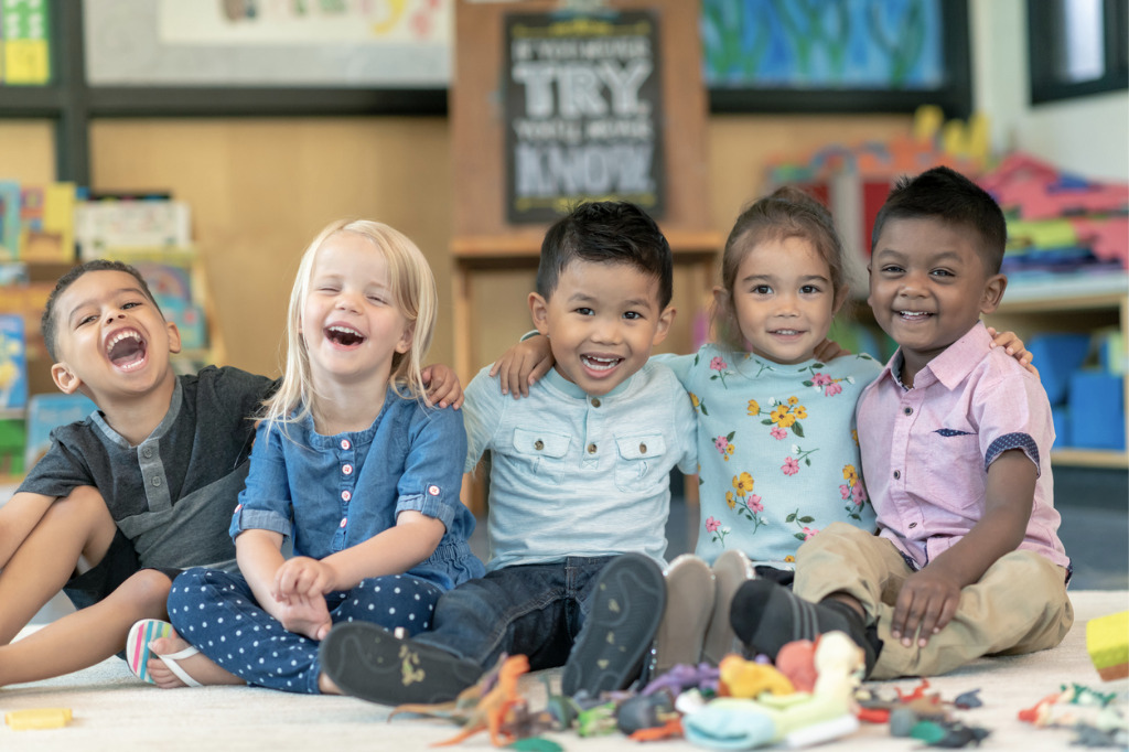 Smiling preschool students sitting on floor