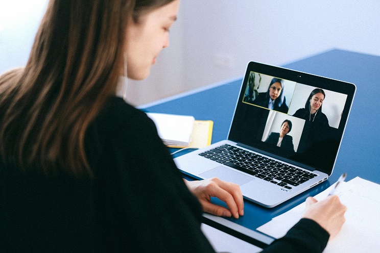 A woman looks at a Zoom meeting on her laptop.