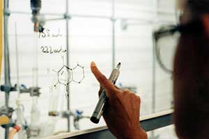 Scientist drawing a chemical structure on a whiteboard