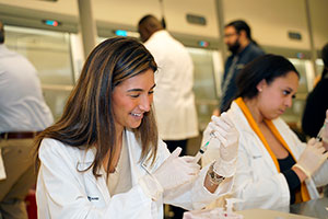 Pharmacy students at a table working with syringes