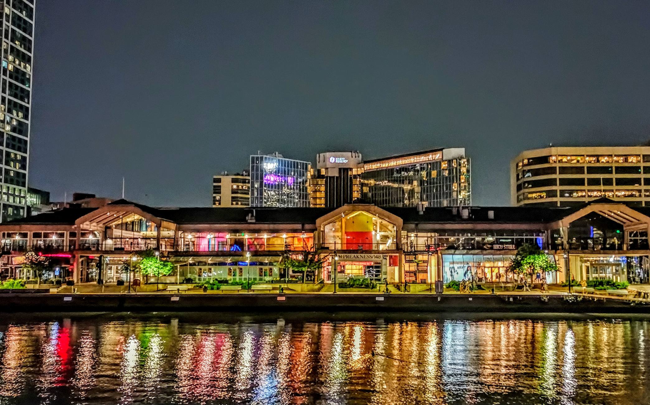 Vivid nighttime photograph of Harborplace along Baltimore’s Inner Harbor by Wamara Mwine.