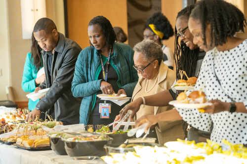 people serving themselves food from a buffet