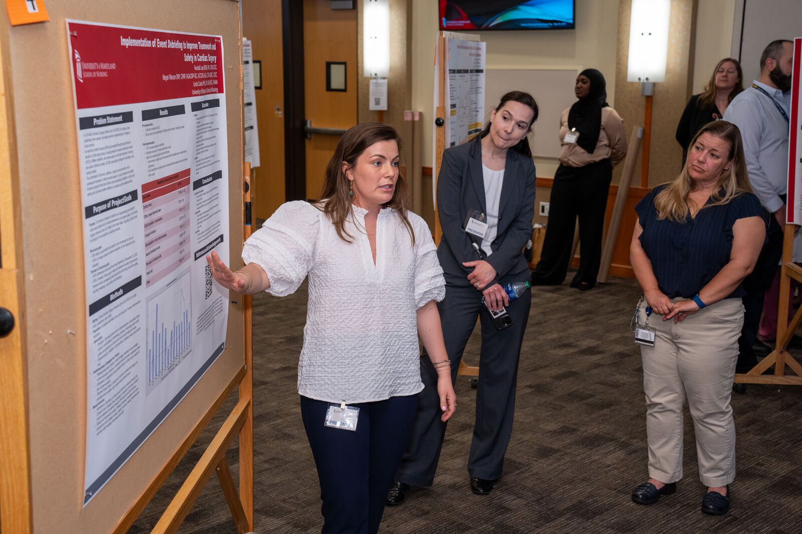 A Doctor of Nursing Practice student pointing at her poster.