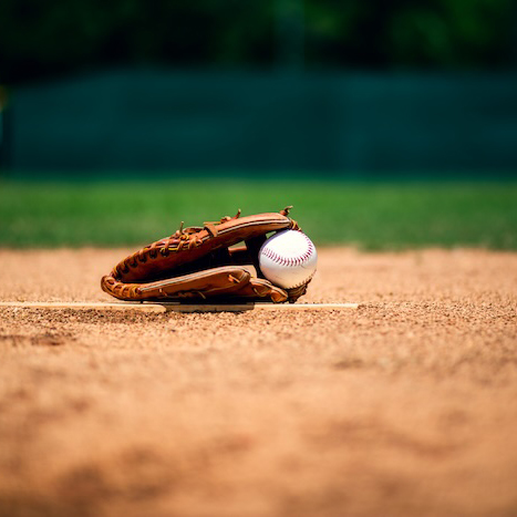 baseball glove and ball lying on dirt on pitcher's mound