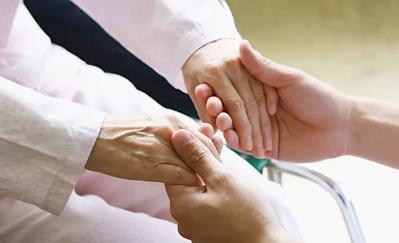 Close-up of two people holding hands to represent compassionate care for older adults with serious illness