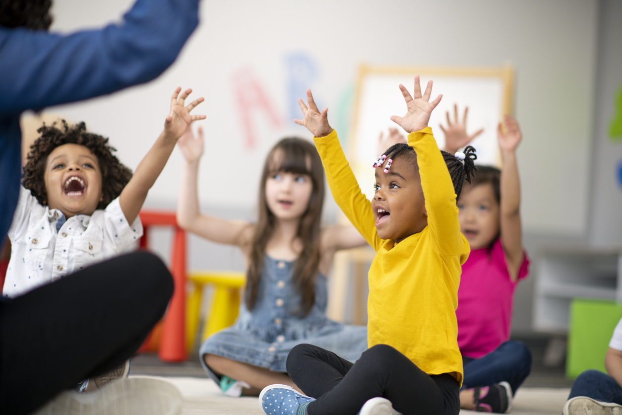 children sitting with arms in the air