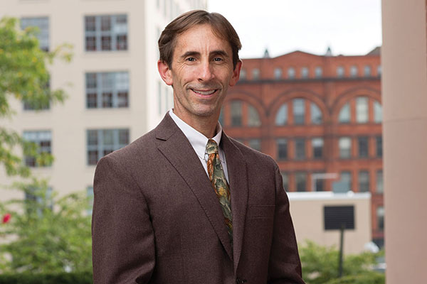 Daniel Mullins standing outside with brick buildings in the background.