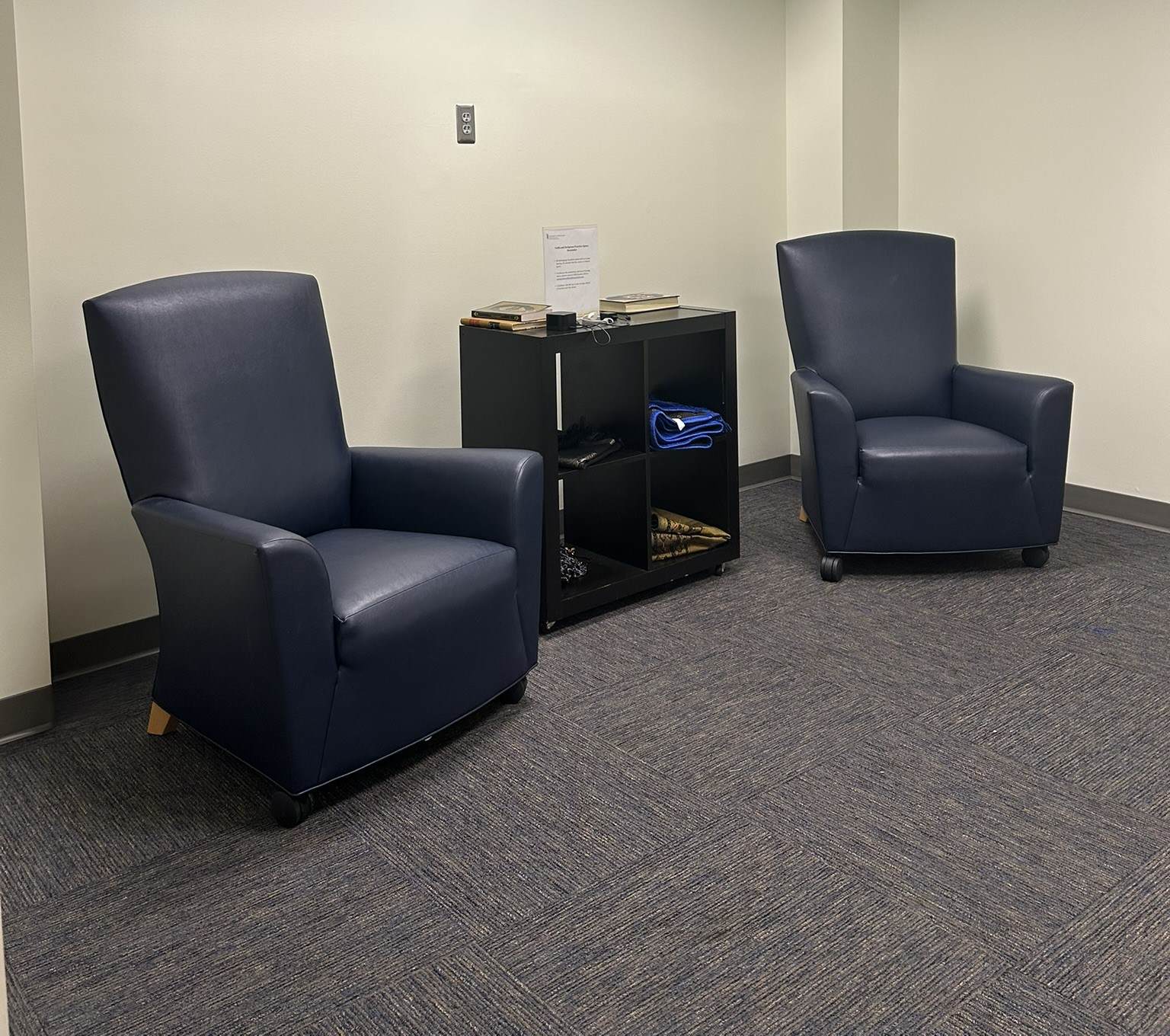 Image of the HSHSL's Faith and Religious Practice Space in Room 301 on the library's third floor. There are two comfortable chairs and a small bookcase for storage.