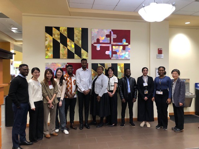 group of PhD students standing in front of Maryland flag wall art
