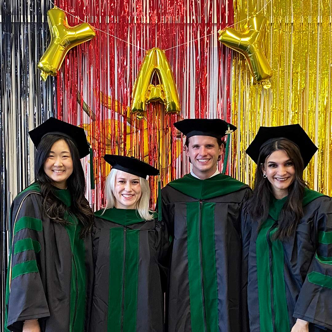 School of Medicine students pose in front of the 2025 grad photo wall at the HSHSL.