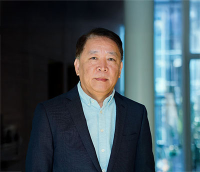 Hongbing Wang standing indoors wearing a dark jacket and collared shirt, with windows in the background.