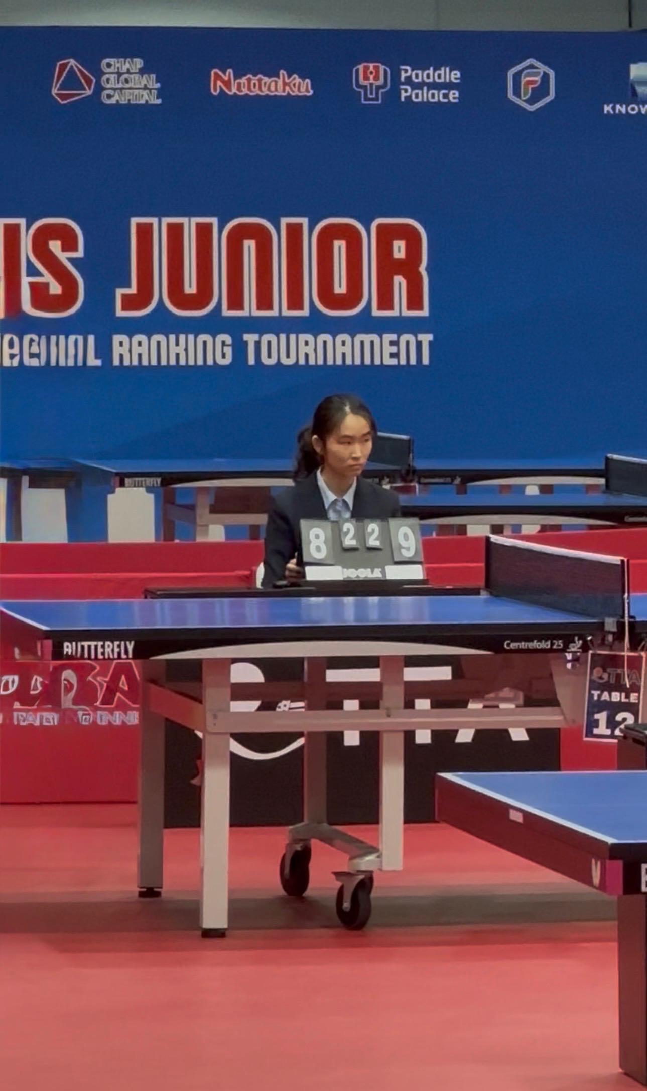 Umpire Stephanie Zhang seated at a score table at a national junior table tennis tournament