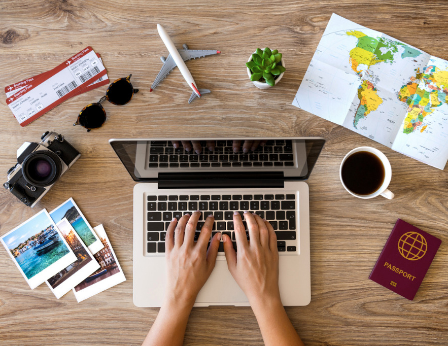 Person typing on laptop with map on the desk and other items