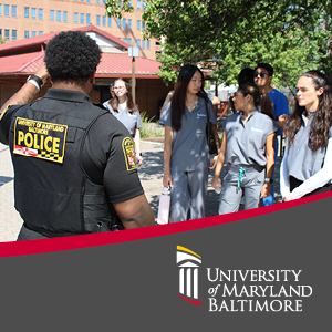 Back of campus police officer talking to students, his police patch is clearly visible on his back