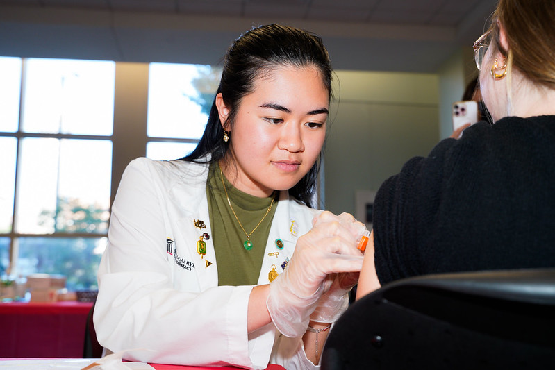 Female pharmacy student administers a vaccine to a patient.