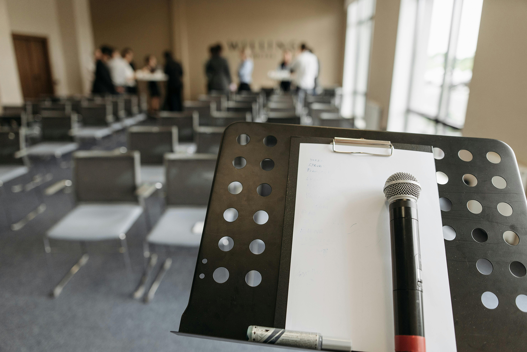 A microphone sits on a podium in front of a room of chairs