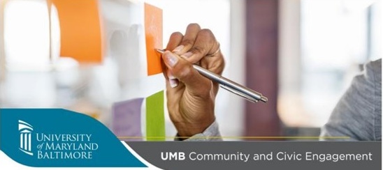 Person writing on an orange note posted on the wall. Their hand and part of their shoulder is showing. They are wearing grey long-sleeved shirt. Other post-in notes are on wall. No writing is visible.